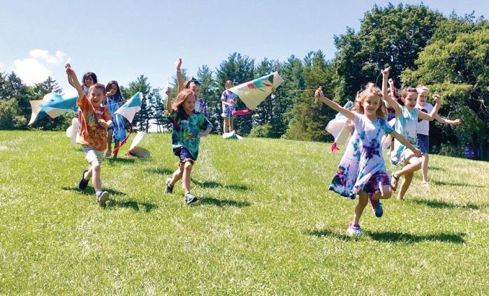 Summer Camp Fun | Kids running down a hill flying kites