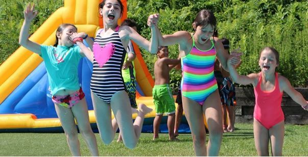 Boston Summer Camps | Girls jumping off a dock into lake water 